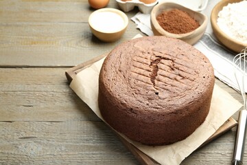 Tasty chocolate sponge cake and ingredients on wooden table