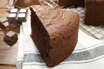 Piece of tasty chocolate sponge cake on wooden table, closeup