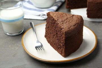 Piece of tasty chocolate sponge cake served on grey table, closeup