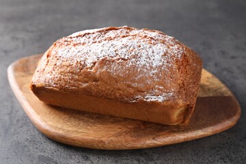 Tasty sponge cake with powdered sugar on grey table, closeup