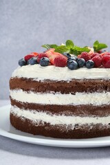 Delicious chocolate sponge cake with berries on light table, closeup