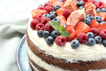 Delicious chocolate sponge cake with berries on white table, closeup