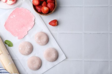 Tasty homemade mochi, dough and strawberries on white tiled table, top view. Space for text