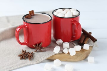 Yummy cocoa with marshmallows and spices on white wooden table