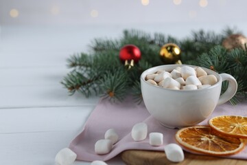 Yummy cocoa with marshmallows in cup, dried orange slices and Christmas wreath on white wooden...