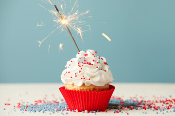 Birthday cupcake with burning sparkler on white table