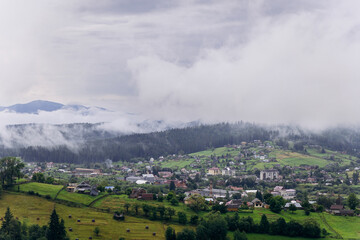Fototapeta premium Misty morning in Vorokhta village with scenic view of Carpathian hills and fog-covered mountains
