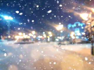 Night city in the snow. Christmas Eve. Blurred evening winter background. Blizzard in the city.