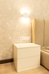 Modern apartment interior featuring a sleek nightstand and elegant wall lighting in a cozy bedroom setting