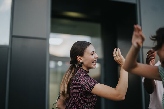 A group of international business people share a joyful moment outdoors in an urban city setting, highlighting teamwork and success.