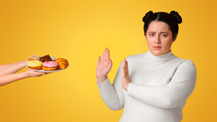 Diet Concept. Fatty girl refusing consume tasty delicious sweets on plate, rejecting unhealthy junk...