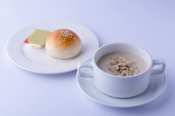 Creamy mushroom soup, smooth texture, in a white bowl, served with buttered bread, on a white backdrop.