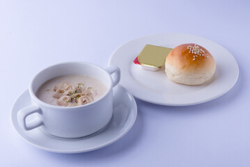 Creamy mushroom soup, smooth texture, in a white bowl, served with buttered bread, on a white...