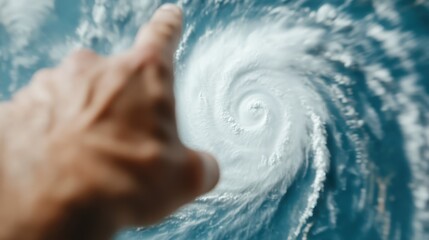 Fototapeta premium A striking image capturing a hand pointing towards a swirling hurricane, showing the power and beauty of nature's most dynamic and destructive force.