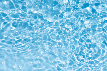 Blue water with ripples on the surface. Defocus blurred transparent blue colored clear calm water surface texture with splashes and bubbles. Water waves with shining pattern texture background.