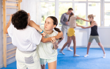 Fototapeta premium Boy and girl training self-defense techniques in group in studio