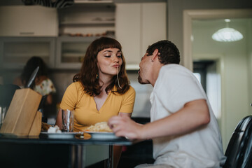 A cheerful couple shares a playful moment with spaghetti during a casual dinner at home, creating a warm and loving atmosphere.