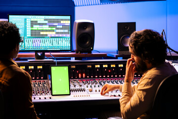 Artist and producer collaborating on new song for an album, looks at isolated display on device...