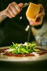 A chef adds fresh Parmesan to a plate. Perfect for Italian restaurant ads, food photography, or cooking videos emphasizing gourmet touches.