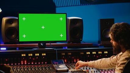 Team of music engineer and artist recording tracks on greenscreen, processing sounds to create a new song. Musician working closely with producer to make high quality tunes. Camera A.