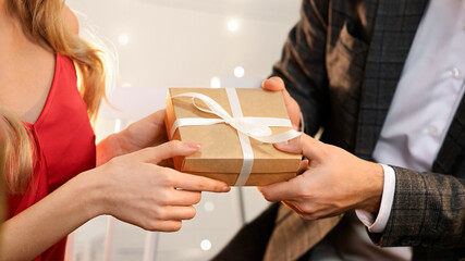 Gift With Love. Man giving box with present to his girlfriend on romantic dinner in restaurant, greeting with Valentine's Day or anniversary, closeup