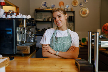 Barista with an apron smiling at the camera in a warm caf setting