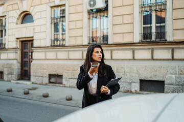 Young businesswoman sending voice message on smartphone on the street	
