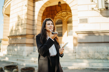Young businesswoman sending voice message on smartphone on the street	