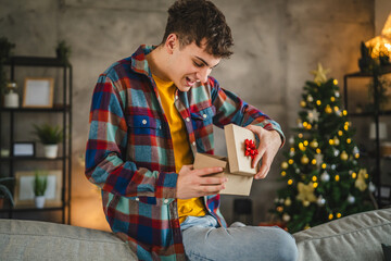 Surprised young adult man open christmas gift at home - Powered by Adobe