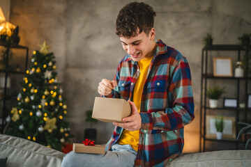 Surprised young adult man open christmas gift at home