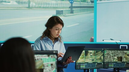 Supervisor gathering intelligence from satellite based surveillance footage, diverse team of operators analyzing traffic through security cameras. Control center license plate reading. Camera A.