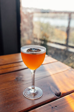 orange cocktail with foam and dehydrated lime in nick and nora glass on outdoor table 