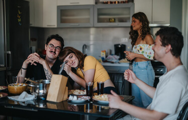A group of friends shares a casual dinner, enjoying each other's company with laughter and conversation in a cozy kitchen setting.