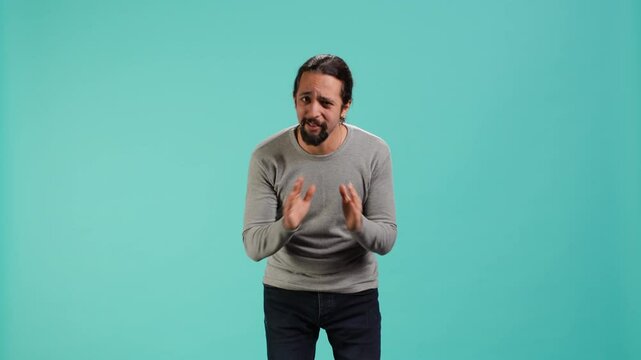 Man putting hands together in begging gesture, making wish, asking for favor from friend, isolated over studio background. Desperate person asking for something, praying and hoping, camera A