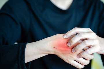 person holding their wrist, showing signs of irritation and discomfort