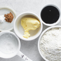 mise en place of ingredients for making molasses cookies, top view of sugar, butter, flour molasses on a marble table, process of making molasses spice cookies