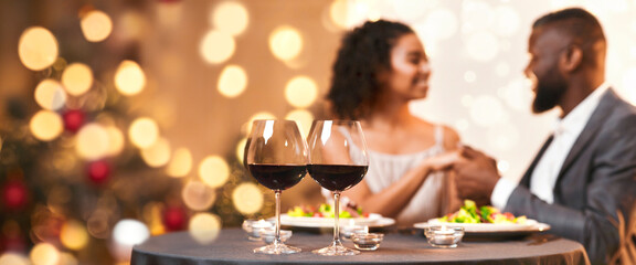 Romantic date at restaurant with candles and wine, black couple in love having festive dinner on Valentine's Day