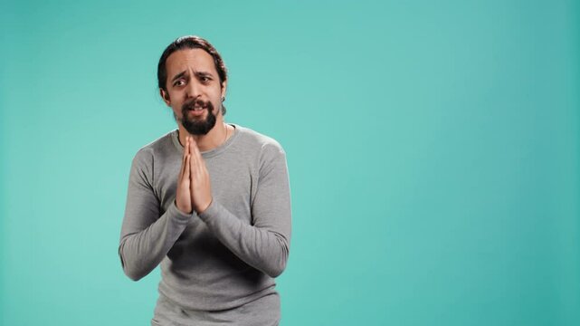 Man putting hands together in apology gesture, asking for forgiveness. Apologetic person doing sorry gesturing, asking for pardon, isolated over studio background, camera B