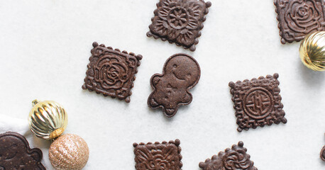 Overhead view of stamped molasses cookies on a parchment lined baking tray, top view of embossed gingerbread cookies on a white background