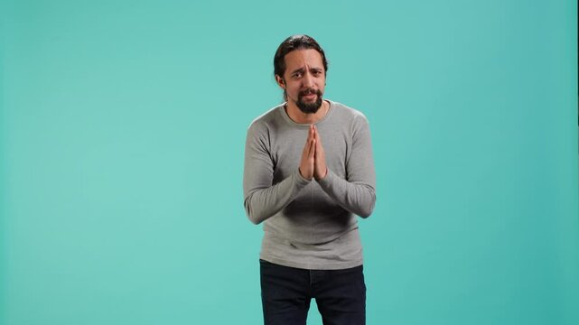 Man putting hands together in apology gesture, asking for forgiveness. Apologetic person doing sorry gesturing, asking for pardon, isolated over studio background, camera A