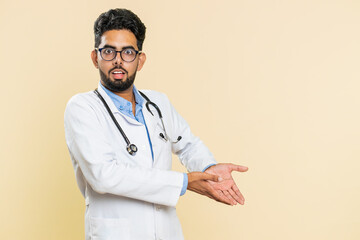 Indian young doctor cardiologist man raising hands asking what why reason of failure, demonstrating...