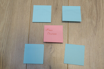 Fototapeta premium Merry Christmas written on sticky notes on a wooden background