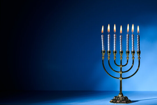 Hanukkah Menorah with burning candles on dark blue background with copy space for text. Jewish holiday Hanukkah celebration concept.