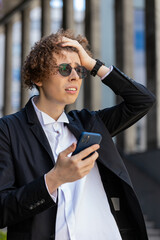 Shocked young businessman using smartphone typing browsing, loses surprised by bad news, fortune...