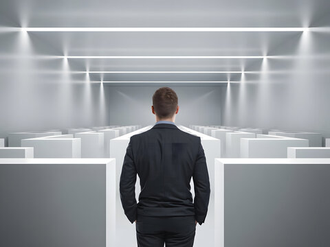 Vista posterior de un hombre de negocios moderno con las manos en los bolsillos, entrando en un laberinto blanco y limpio como espacio de oficina
