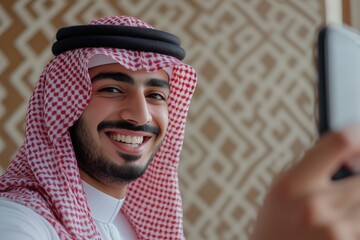 Young saudi man taking selfie on his phone and smiling