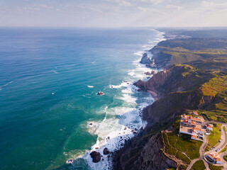 View from drone of rocky Atlantic coast of Cabo da Roca with lighthouse in sunny day, Portugal