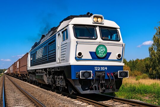 A powerful locomotive pulling a line of freight wagons, rumbling through a countryside landscape, with the rhythmic clatter of steel wheels on the tracks