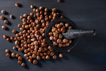 Raw hazelnuts in a stone mortar against a dark background