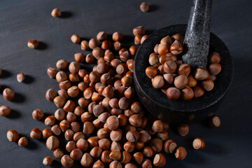Raw hazelnuts in a stone mortar against a dark background